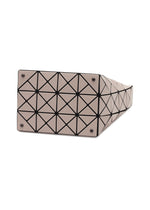 The VALLEY handbag by BAO BAO ISSEY MIYAKE in beige features a gusseted bottom with a black geometric grid of triangles and four metal studs at each corner for upright support.