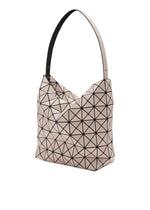 The VALLEY tote bag by BAO BAO ISSEY MIYAKE features a beige geometric design with a black triangular grid, angular folded edges, a sculptural gusseted shape, and a single wide handle for easy carrying.