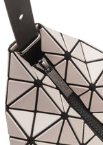Close-up of VALLEY by BAO BAO ISSEY MIYAKE, a geometric gusseted handbag with glossy light triangles outlined in black, triangular panels, visible zipper, and a black strap attached by a metal loop at the corner.
