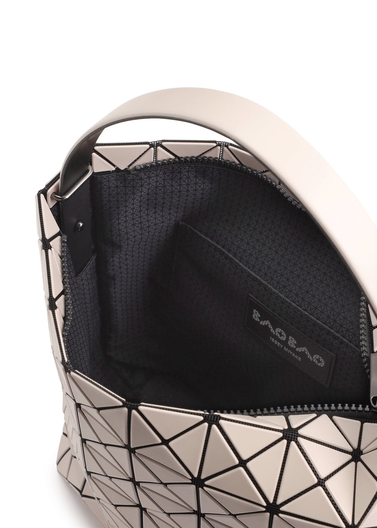 A close-up of the VALLEY handbag by BAO BAO ISSEY MIYAKE shows its geometric-patterned gusset, wide handle, black interior lining, and inner pocket with a branded label. The bag stands upright for easy access. view 5 of 6