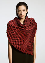 A person with straight, dark hair wears the TYPE-O STOLE by A-POC ABLE ISSEY MIYAKE in deep red, its sculptural three-dimensional pattern wrapping around their shoulders against a plain, light background that highlights the intricate fabric design.