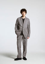 A person with curly hair stands against a plain background wearing the TYPE-U 001 jacket by A-POC ABLE ISSEY MIYAKE, paired with a black shirt and shoes, hands in pockets, looking at the camera.