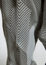 Close-up of TYPE-O 010 by A-POC ABLE ISSEY MIYAKE: gray recycled polyester fabric featuring a raised, geometric zigzag and chevron pattern for a textured, three-dimensional surface.