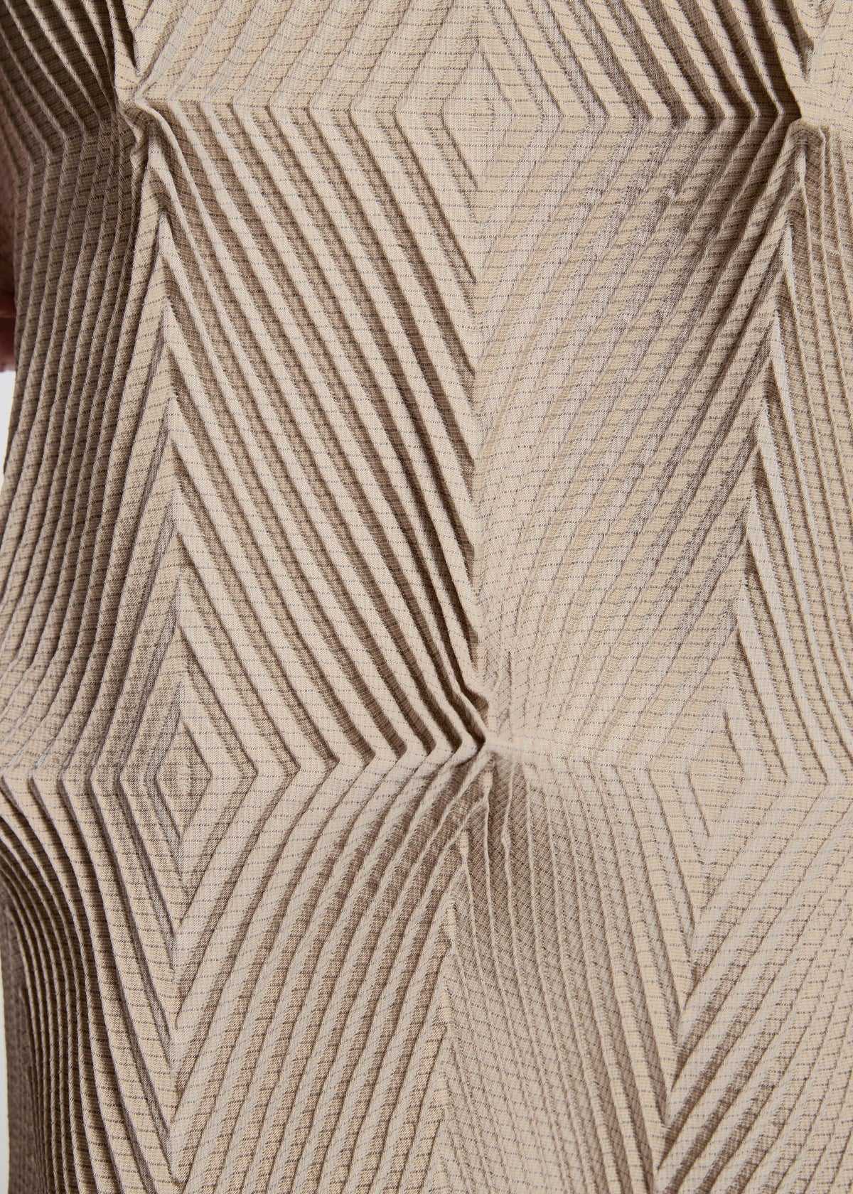 TYPE-O 007 by A-POC ABLE ISSEY MIYAKE features a textured beige surface with a geometric pattern of raised, intersecting diagonal lines, forming diamond and square shapes for a striking three-dimensional optical illusion. view 10 of 10