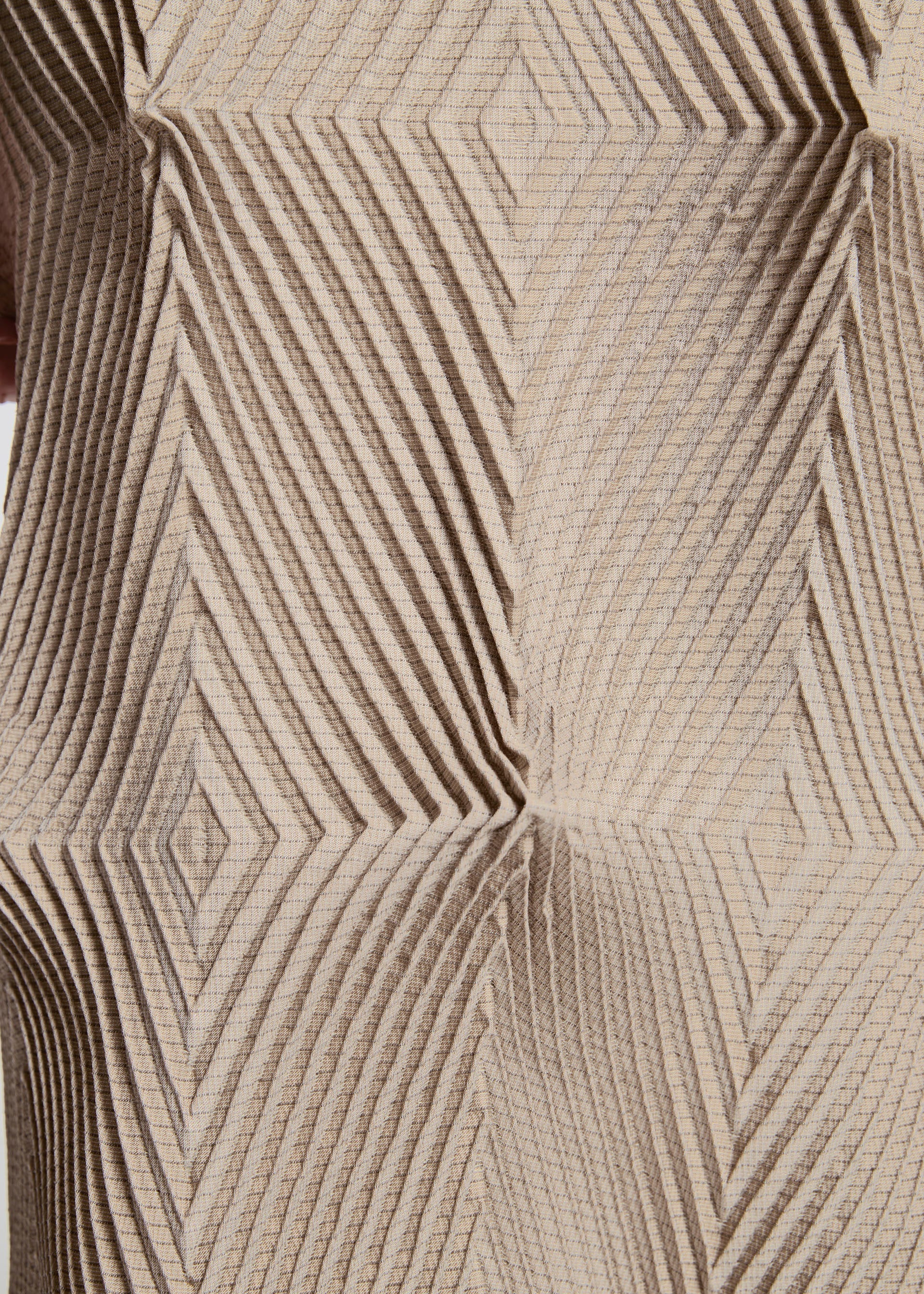 Zoomed view TYPE-O 007 by A-POC ABLE ISSEY MIYAKE features a textured beige surface with a geometric pattern of raised, intersecting diagonal lines, forming diamond and square shapes for a striking three-dimensional optical illusion.