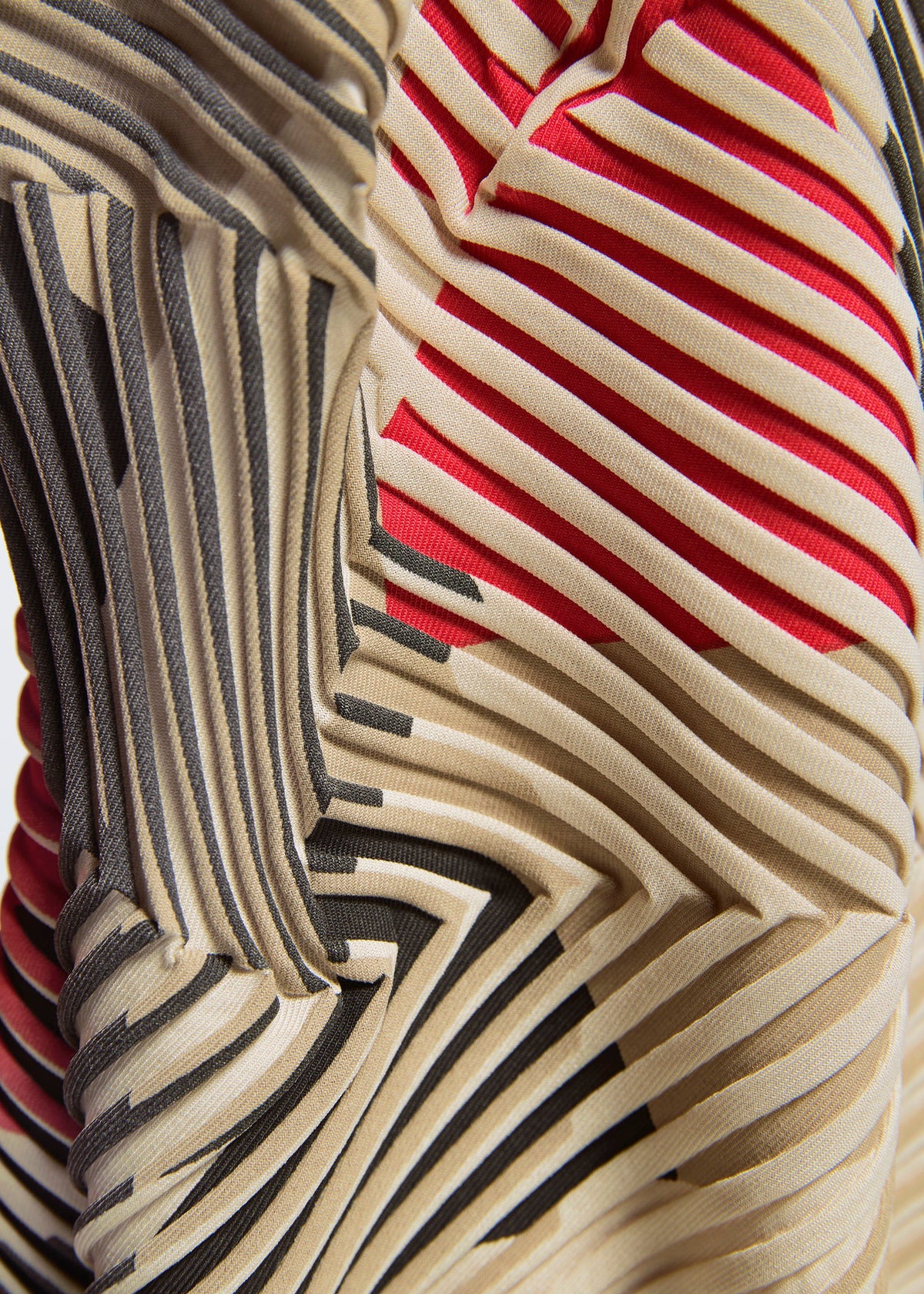 Close-up of the TYPE-P 002 dress by A-POC ABLE ISSEY MIYAKE, crafted with Baked Stretch, featuring bold geometric pleats in beige, black, and red for a striking three-dimensional abstract pattern. view 6 of 6