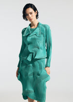 A person with short dark hair models the TYPE-O 003 teal dress by A-POC ABLE ISSEY MIYAKE, made from recycled polyester with layered, pleated fabric for a 3D wavy effect, standing against a plain white background.
