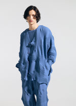 A person with short, wavy dark hair wears the TYPE-P 003-1 by A-POC ABLE ISSEY MIYAKE—loose-fitting blue textured pants and top—posing with hands in pockets against a plain background. A versatile choice for everyday wear.