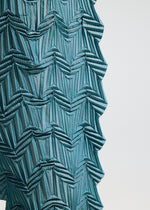 Close-up of TYPE-O 019 by A-POC ABLE ISSEY MIYAKE: blue fabric with geometric, zigzag, and layered patterns. The structured, three-dimensional effect resembles zigzag pleat pants crafted with the Steam Stretch technique.
