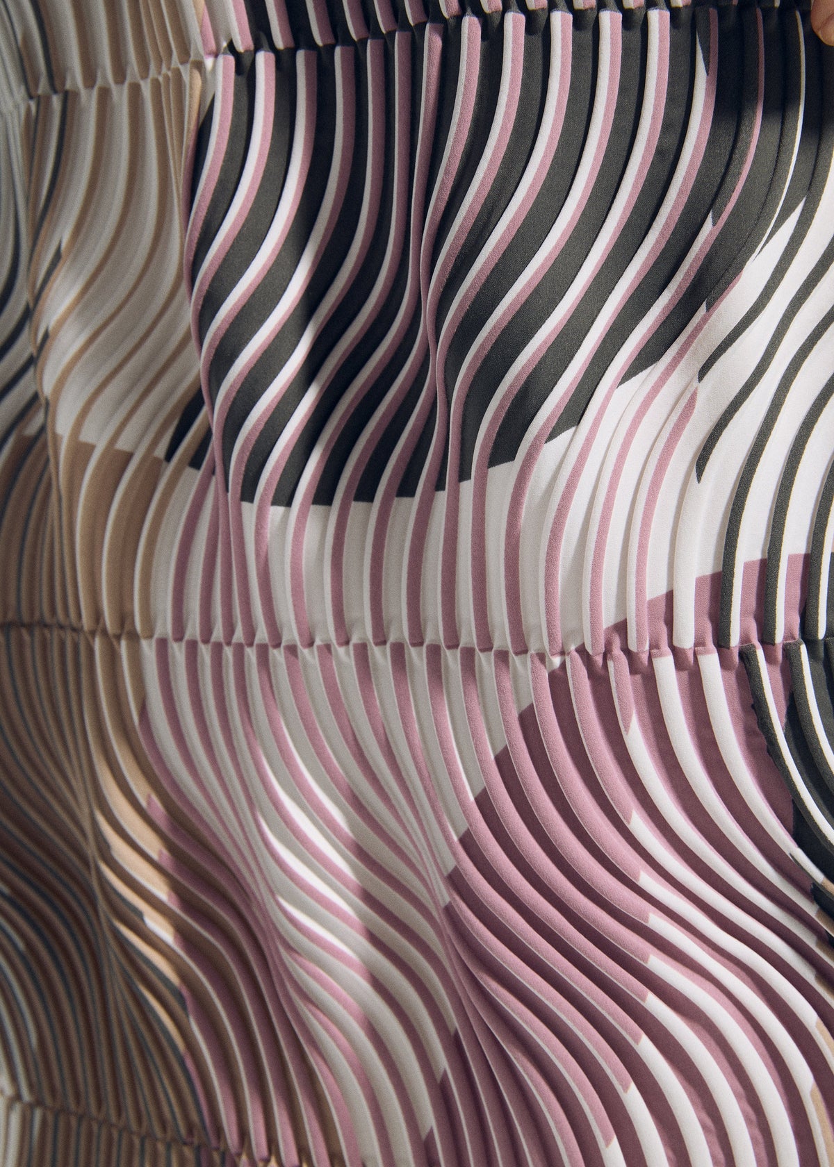 A close-up of TYPE-P 005 fabric by A-POC ABLE ISSEY MIYAKE shows wavy pleats and abstract patterns in pink, black, beige, and white. Dynamic lines create a Baked Stretch effect for striking depth and movement. view 9 of 9