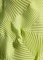 Close-up of TYPE-P 003-2 by A-POC ABLE ISSEY MIYAKE: yellow-green fabric with Baked Stretch technique, featuring geometric pleats and zigzag patterns that create a dynamic three-dimensional effect.