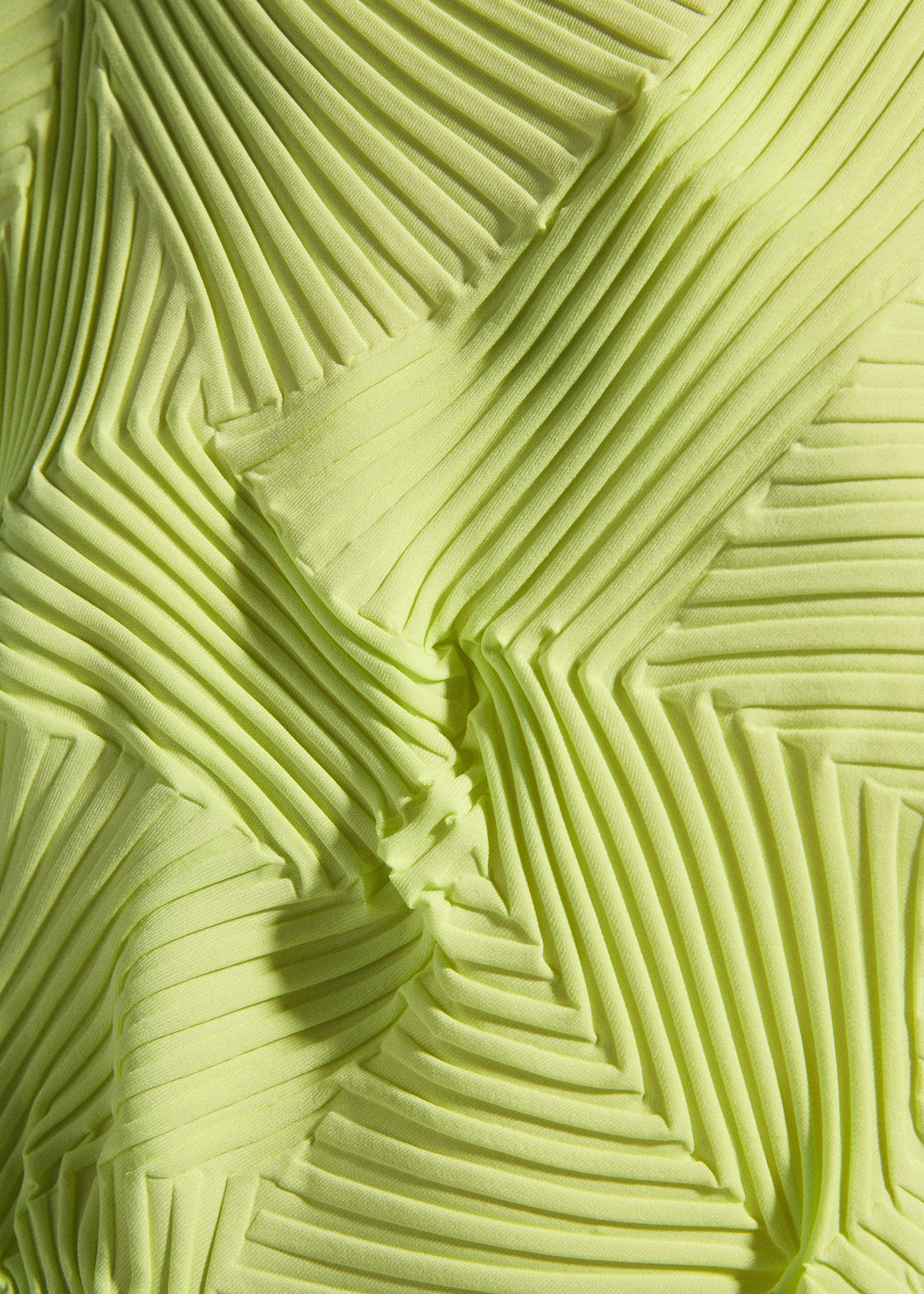 Zoomed view Close-up of TYPE-P 003-2 by A-POC ABLE ISSEY MIYAKE: yellow-green fabric with Baked Stretch technique, featuring geometric pleats and zigzag patterns that create a dynamic three-dimensional effect.