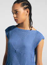 A person with braided hair wears the TYPE-P 003-1 textured blue pleated dress by A-POC ABLE ISSEY MIYAKE, looking to the side against a plain light background.