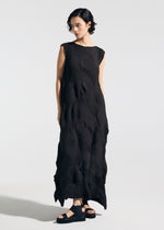 A person with short dark hair models the TYPE-P 003-1 dress by A-POC ABLE ISSEY MIYAKE— a sleeveless, pleated piece with textured geometric folds—paired with black sandals against a plain light background.
