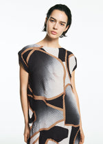 A person with short dark hair wears the TYPE-XV SOAR NY project 001 dress by A-POC ABLE ISSEY MIYAKE, featuring a geometric black, brown, and white pattern with a Japanese aesthetic, standing against a plain white background.