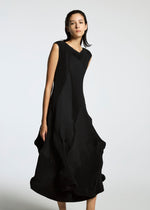A woman with straight, dark hair wears the TYPE-Ⅰ 008 dress by A-POC ABLE ISSEY MIYAKE. The black textured dress flares at the hem as she stands against a white background, confidently facing the camera.