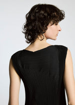 A person with short, curly dark hair, viewed from behind and in slight profile, wears a black textured A-POC ABLE ISSEY MIYAKE TYPE-Ⅰ 008 dress against a neutral background.