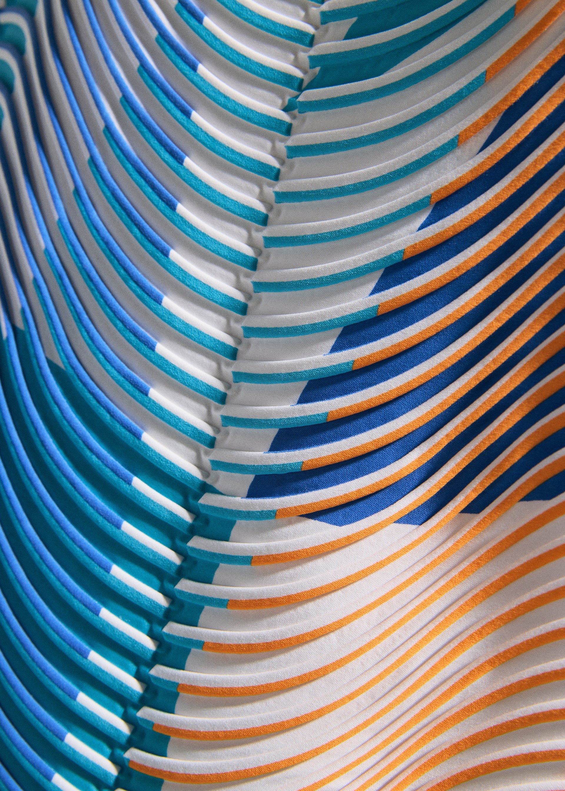 Zoomed view Close-up of TYPE-P 005 by A-POC ABLE ISSEY MIYAKE shows a patterned surface with raised, curved lines in blue, teal, orange, and white. The dynamic, wavy lines form a layered, symmetrical design.