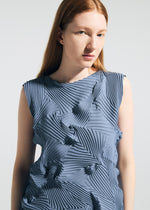 A woman with long red hair wears the TYPE-P 003-2 sleeveless blue top by A-POC ABLE ISSEY MIYAKE, featuring geometric pleated patterns made with the Baked Stretch technique, as she gazes to the side against a plain light background.