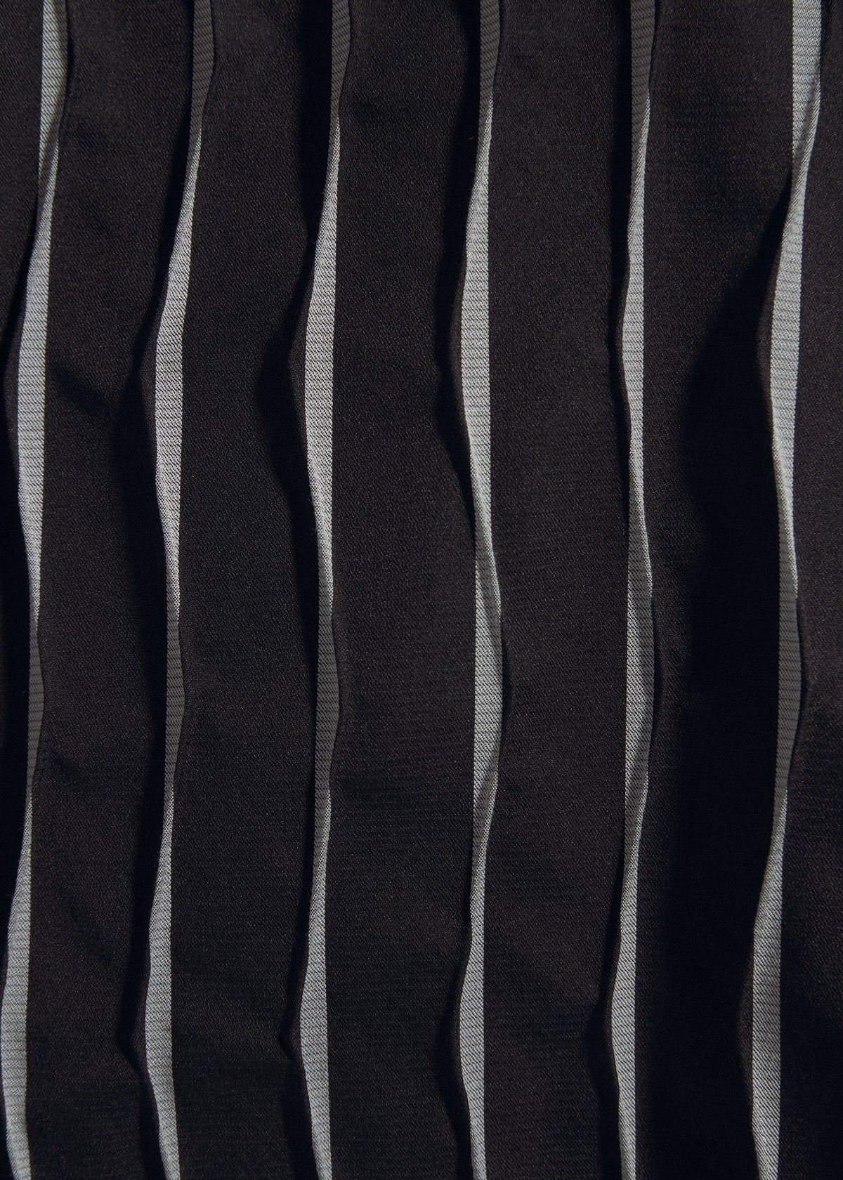 A close-up of TYPE-W 011 by A-POC ABLE ISSEY MIYAKE: vertically striped black and gray fabric with zigzag pleats, featuring a wrinkled, textured surface inspired by Steam Stretch techniques. view 9 of 10