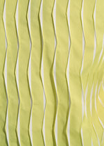 Close-up of TYPE-W 011 by A-POC ABLE ISSEY MIYAKE features yellow fabric with zigzag pleats and a wavy texture. The vertical folds create shadows and highlights, showcasing the fabric's three-dimensional Steam Stretch effect.