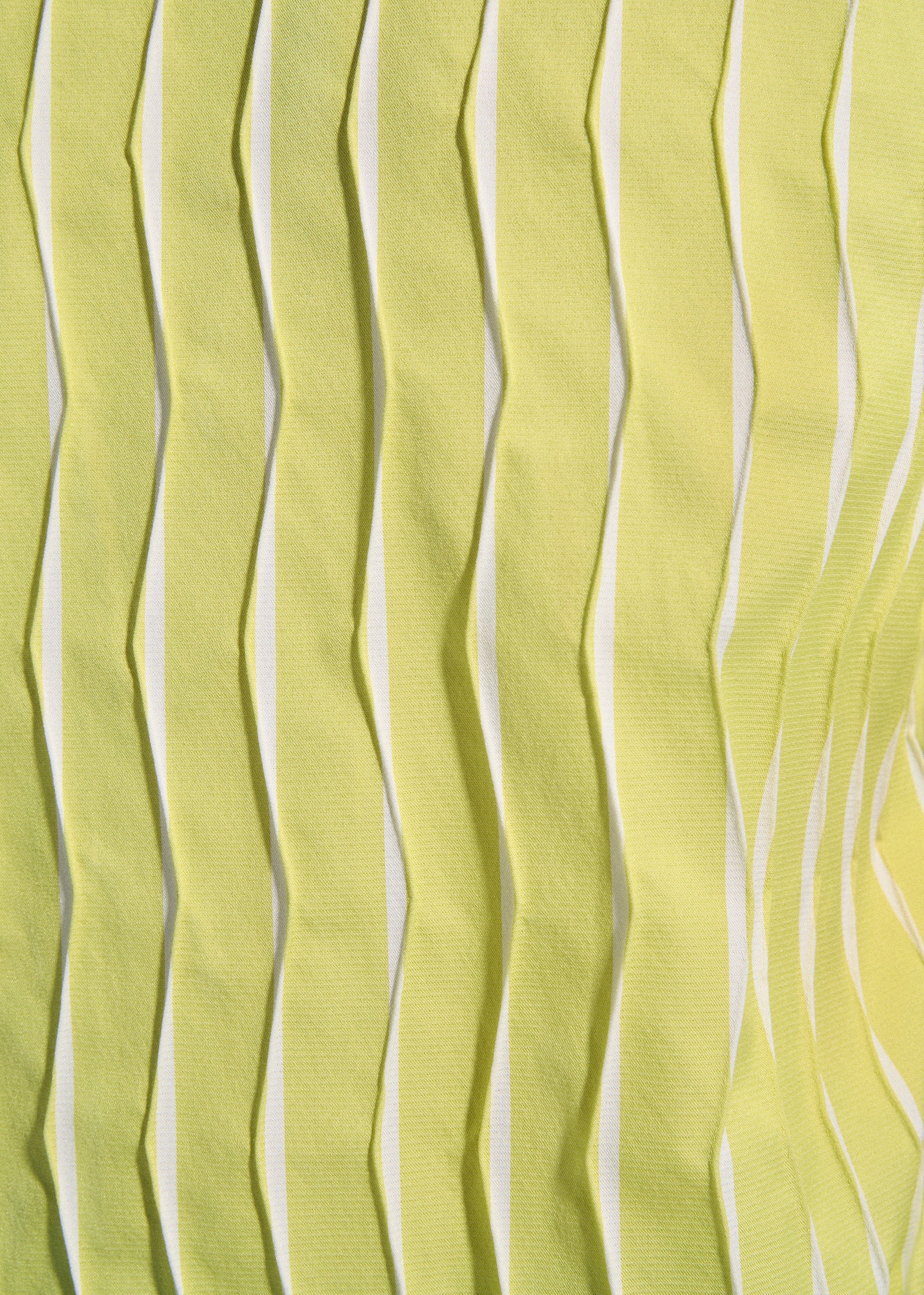 Zoomed view Close-up of TYPE-W 011 by A-POC ABLE ISSEY MIYAKE features yellow fabric with zigzag pleats and a wavy texture. The vertical folds create shadows and highlights, showcasing the fabric's three-dimensional Steam Stretch effect.