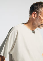 A man with short hair, a beard, and glasses wears the TYPE-J 001 two-tone knit oversized t-shirt by A-POC ABLE ISSEY MIYAKE, shown from the side against a light background with his face partially out of frame.