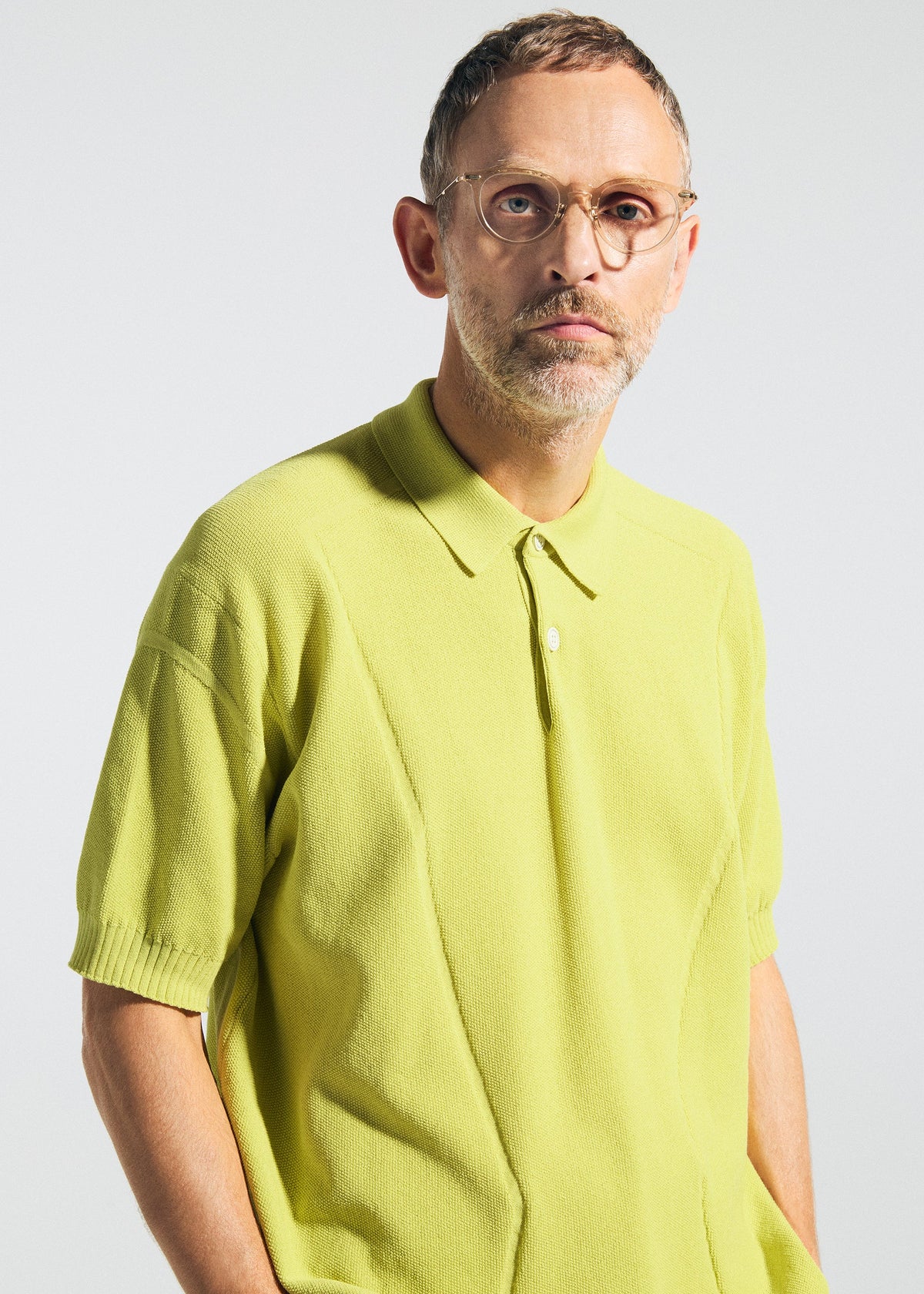 A man with short hair, glasses, and a trimmed beard wears the TYPE-K 003-2 knit polo shirt by A-POC ABLE ISSEY MIYAKE, looking at the camera against a plain light background. view 4 of 6