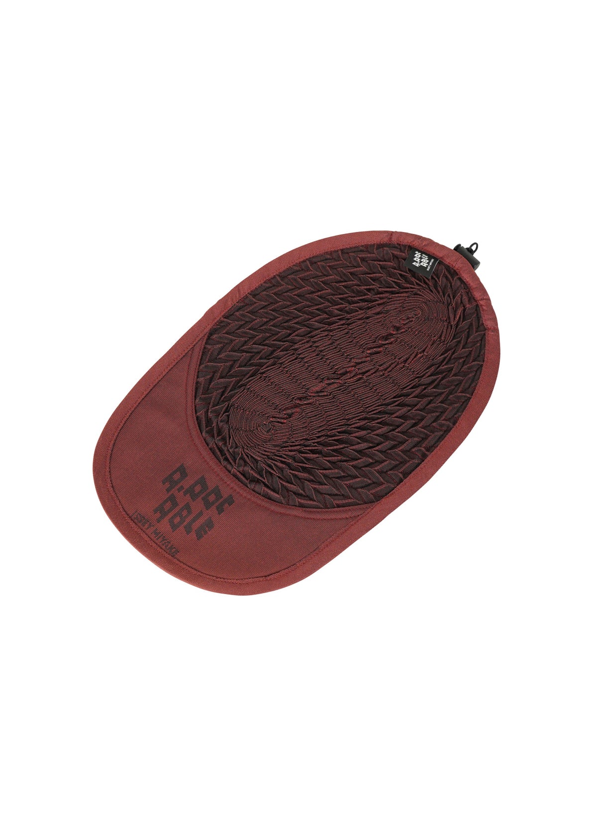 A maroon, oval-shaped TYPE-O CAP by A-POC ABLE ISSEY MIYAKE with geometric pleats, a mesh center, black clasp, and PORT ALIVE text on the brim. The adjustable hat is laid flat on a white background. view 9 of 16