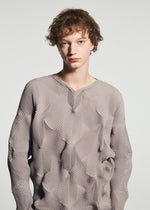 A young person with short, curly brown hair wears the TYPE-O 010-1 by A-POC ABLE ISSEY MIYAKE, a textured light mauve pleated long-sleeved top with a star pattern, standing against a plain light gray background.