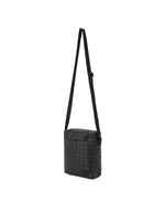 The VOYAGER by BAO BAO ISSEY MIYAKE is a small black vertical shoulder bag with an adjustable strap and a distinctive geometric triangular pattern on its exterior. Designed for convenience, it includes water bottle storage and is shown against a plain white background.
