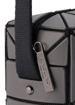 Close-up of the CUBOID shoulder bag by BAO BAO ISSEY MIYAKE, featuring a gray geometric pattern, black adjustable strap, silver engraved zipper pull, and metal snap button on its minimalist design.