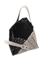 The PRISM MATTE-2 by BAO BAO ISSEY MIYAKE is a geometric silver and black tote bag with triangular patterns and a fabric grain texture, featuring two handles, an A4-friendly spacious interior, a zip pocket, and the brand label.
