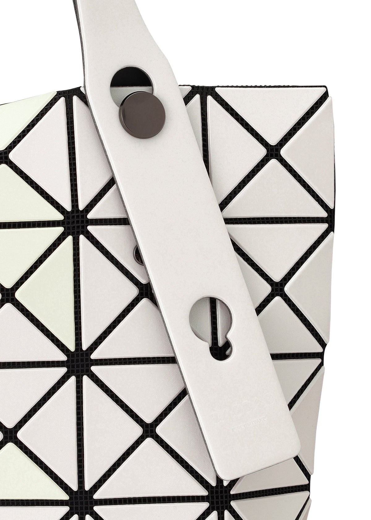 Close-up of the BAO BAO ISSEY MIYAKE PRISM MATTE-2 tote, featuring white triangular panels with black lines and a white strap detailed with metallic buttons and cut-outs, suggesting a handy zippered interior pocket. view 5 of 8