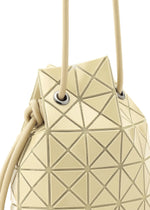 Close-up of the WRING ONE-TONE by BAO BAO ISSEY MIYAKE—a beige geometric shoulder bag with triangular patterns, cord handles, and metallic grommets. Its modern, structured design features a textured, shiny surface.