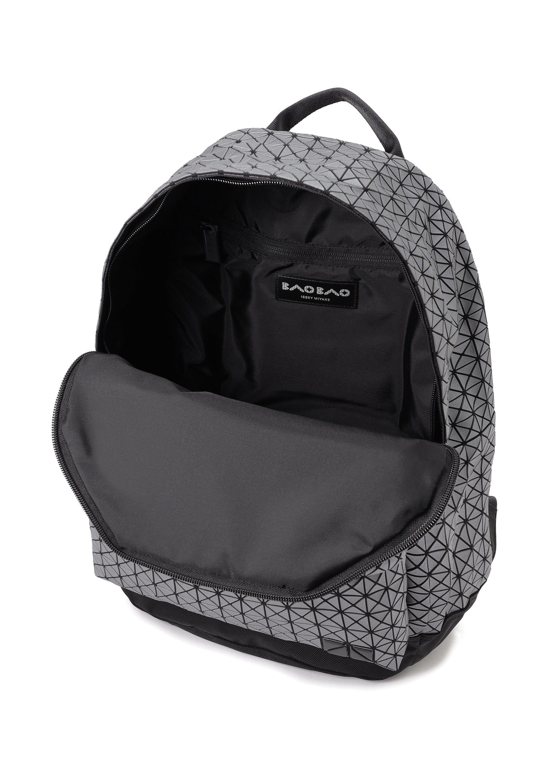 Zoomed view The DAYPACK REFLECTOR by BAO BAO ISSEY MIYAKE is a geometric-patterned gray and black unisex backpack with its main zipper open, showing a spacious interior and iconic branding.