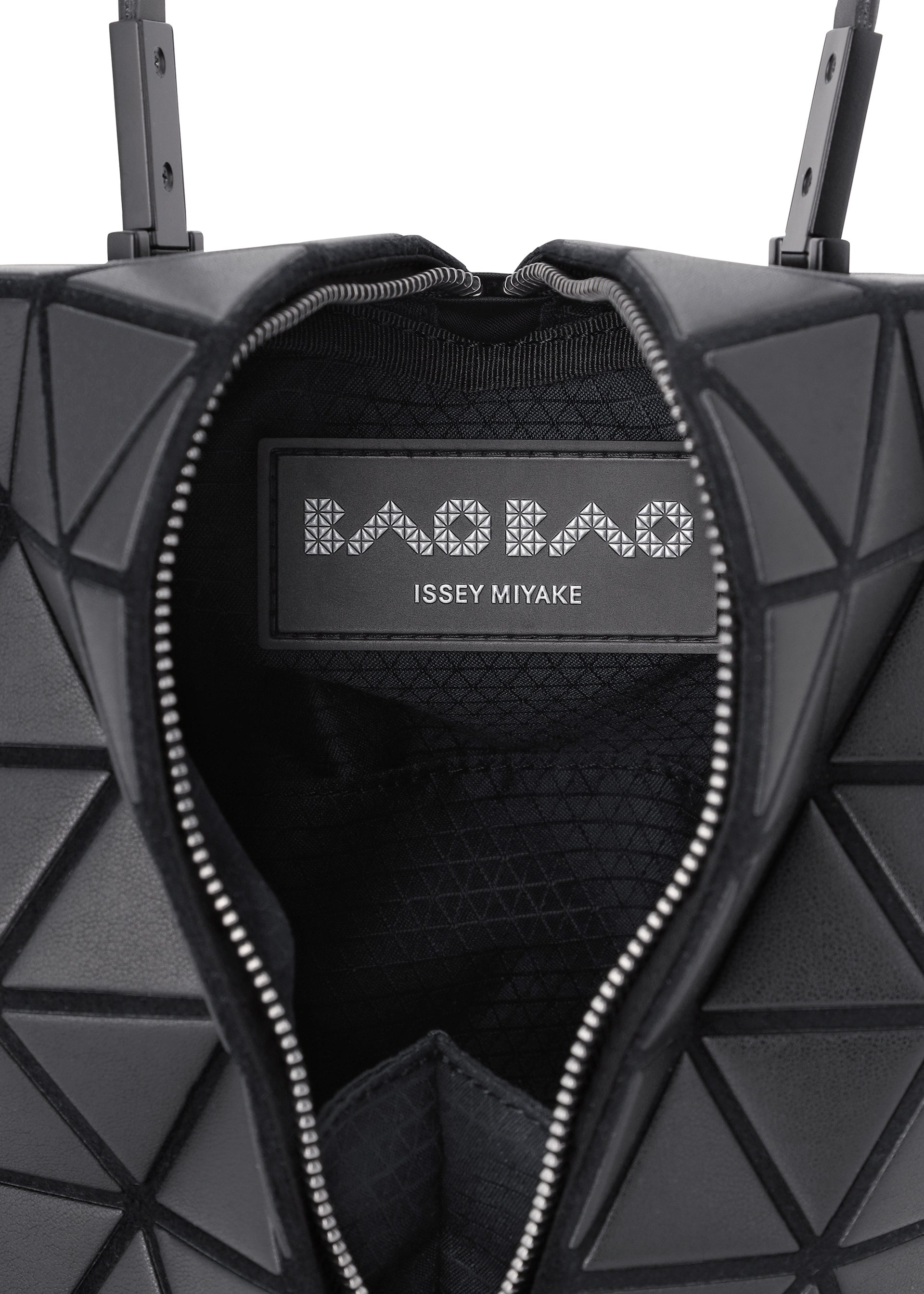 Zoomed view Close-up of the BAO BAO ISSEY MIYAKE TORSO handbag: a black equilateral triangle shape with a geometric pattern, open zipper, and visible inner label.