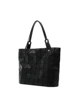 The BAO BAO ISSEY MIYAKE ROCK MATTE is a black tote bag with geometric triangular patterns, two matching handles, and a gusseted bottom for extra space—ideal for carrying your 13-inch laptop. Shown on a white background.