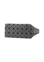 The image shows the base of the VALLEY handbag by BAO BAO ISSEY MIYAKE, a black rectangular design with a shiny geometric triangular grid and small metal feet at each corner for stability.