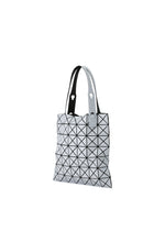 The BAO BAO ISSEY MIYAKE PRISM FROST tote bag features black triangle lines on a white matte surface, two white handles with metal rivets, and is displayed against a plain white background.