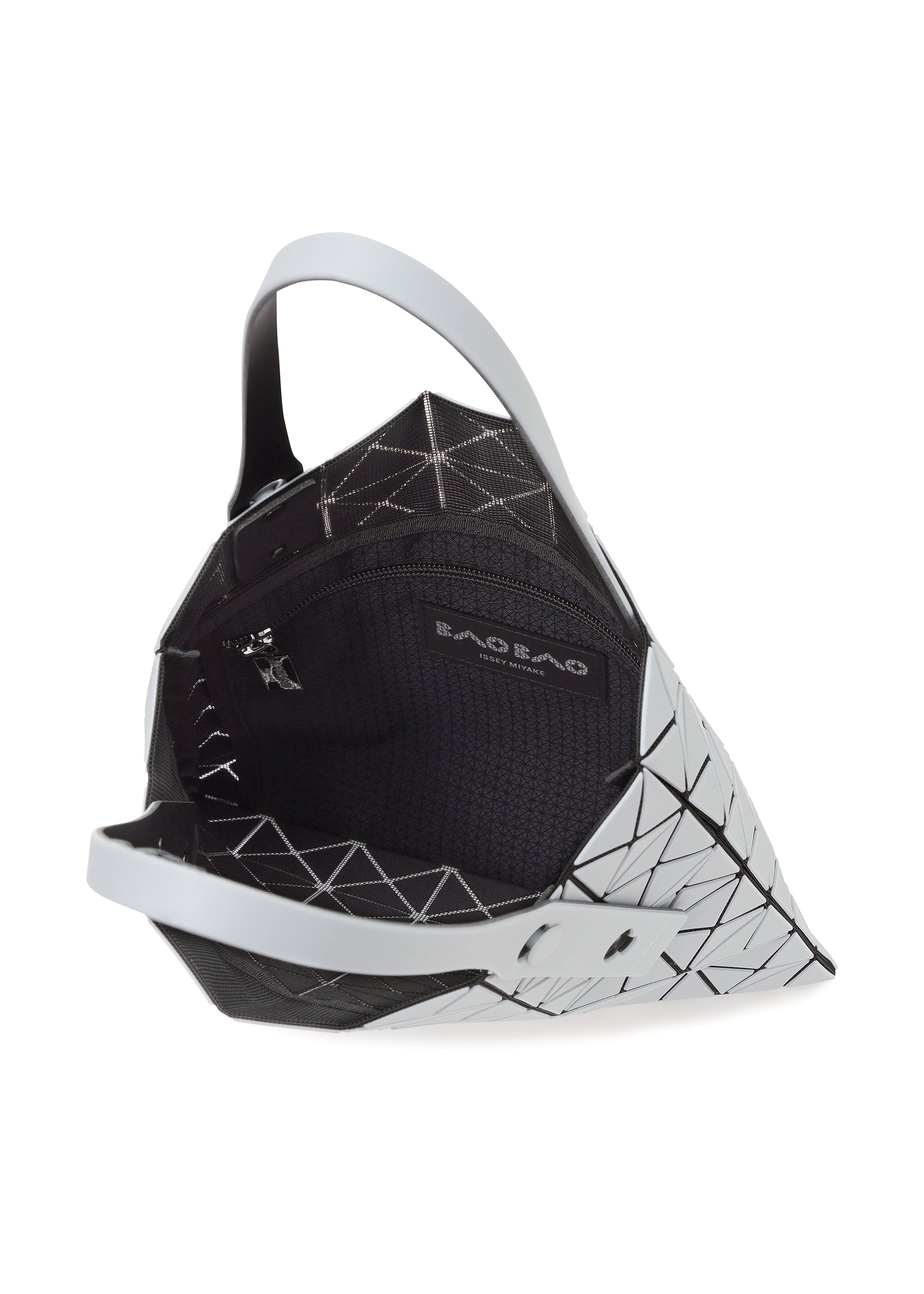 Zoomed view The PRISM FROST tote by BAO BAO ISSEY MIYAKE features a geometric white and black design, matte flexible triangular panels, a black interior, and an inner zip pocket labeled BAO BAO. The bag is partially open to show its details.