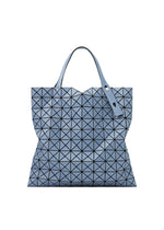 The PRISM DENIM tote by BAO BAO ISSEY MIYAKE features a geometric blue triangular pattern, denim fabric, two handles, a modern structured shape, and a zippered interior pocket. - BLUE （no.72）