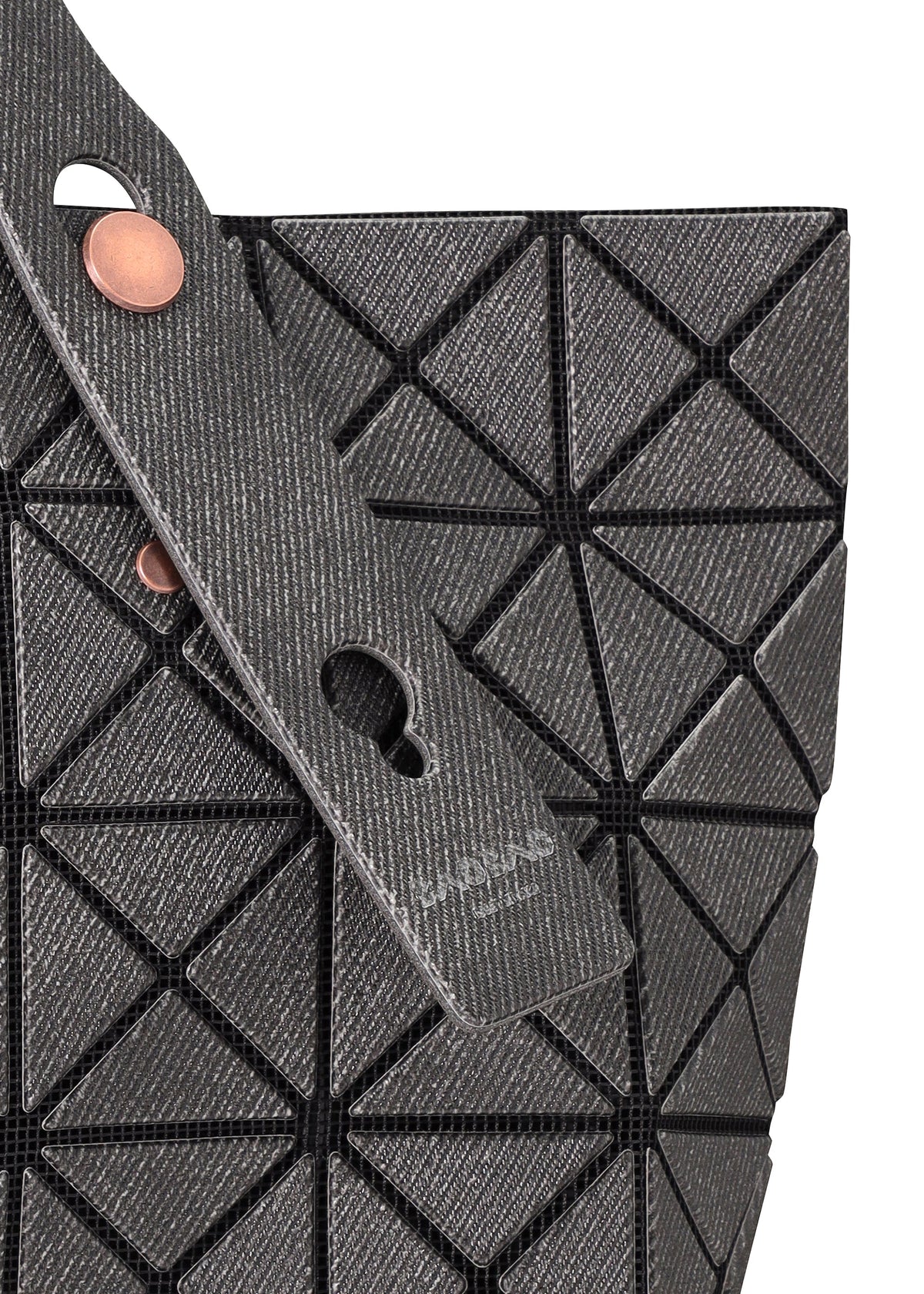 Close-up of the PRISM DENIM tote by BAO BAO ISSEY MIYAKE, featuring a gray geometric design with triangular panels, black grid lines, two textured straps with circular metal fasteners, and a zippered interior pocket for secure storage. view 4 of 7