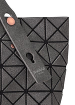 Close-up of the PRISM DENIM tote by BAO BAO ISSEY MIYAKE, featuring a gray geometric design with triangular panels, black grid lines, two textured straps with circular metal fasteners, and a zippered interior pocket for secure storage.