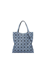 The PRISM DENIM tote bag by BAO BAO ISSEY MIYAKE features a blue geometric triangular pattern with black lines, two handles (one with a snap), a zippered inside pocket, and a modern minimalist design, shown on a white background. - BLUE （no.72）