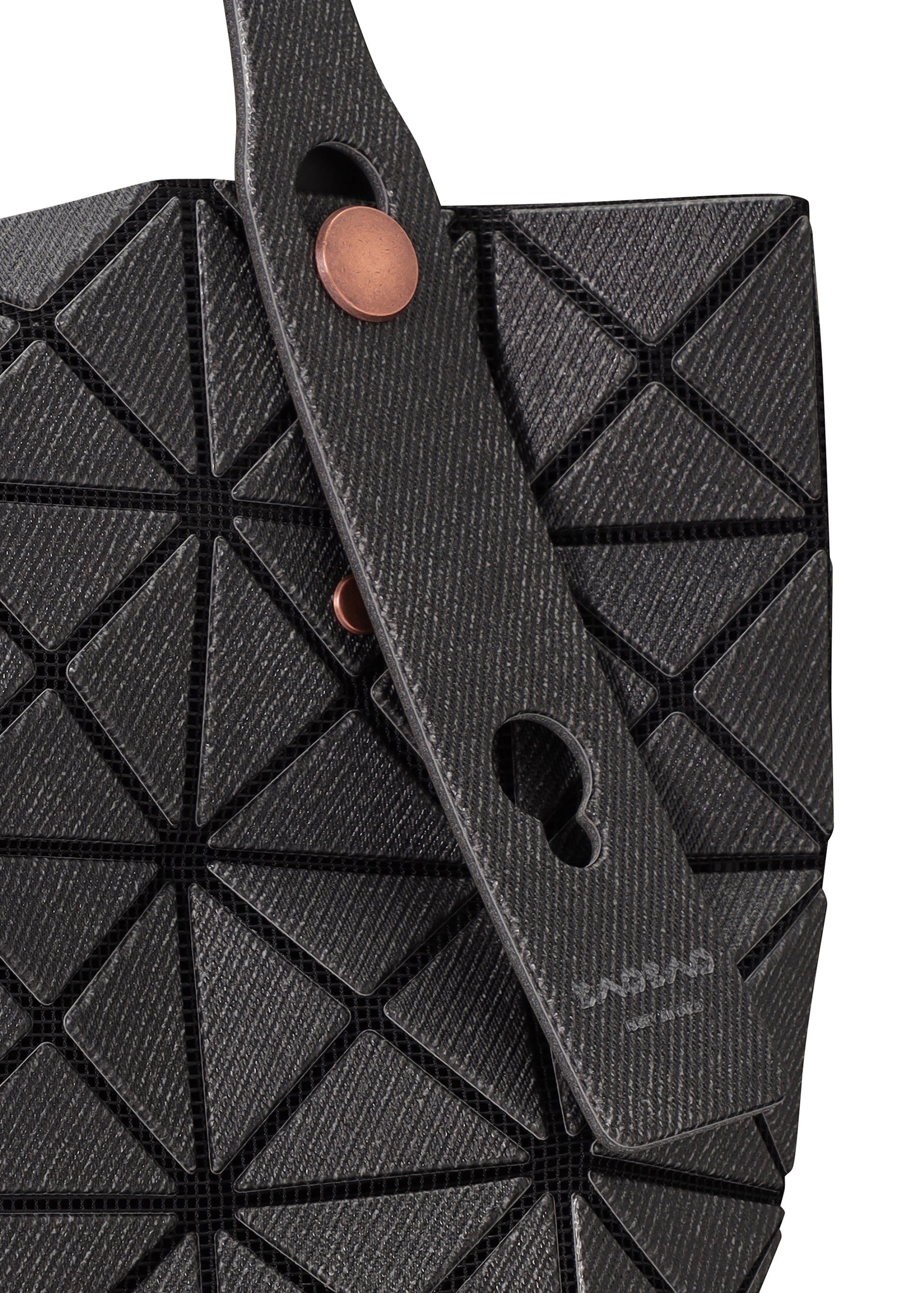 Zoomed view Close-up of the BAO BAO ISSEY MIYAKE PRISM DENIM tote bag featuring black geometric triangular panels, a textured strap with two copper buttons, subtle branding near the handle, and a secure zippered inside pocket.