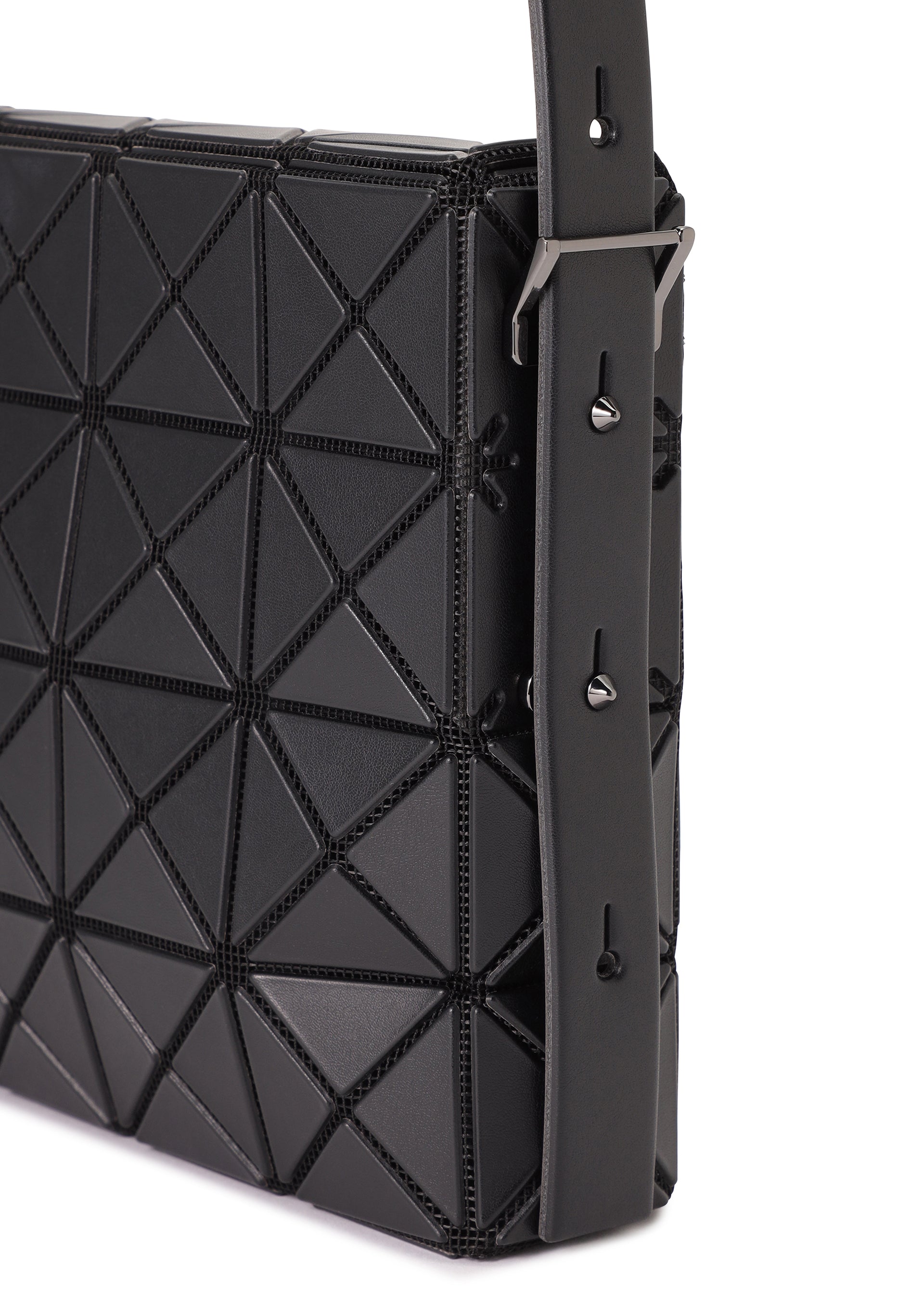 Zoomed view Close-up of OBLONG by BAO BAO ISSEY MIYAKE, a black minimalist handbag with a geometric triangular pattern, wide strap with metal buckles and adjustable holes, set against a clean white background.