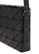 Close-up of the OBLONG handbag by BAO BAO ISSEY MIYAKE, featuring a black geometric triangular pattern, detailed stitching, and an adjustable strap with metal hardware and multiple holes.
