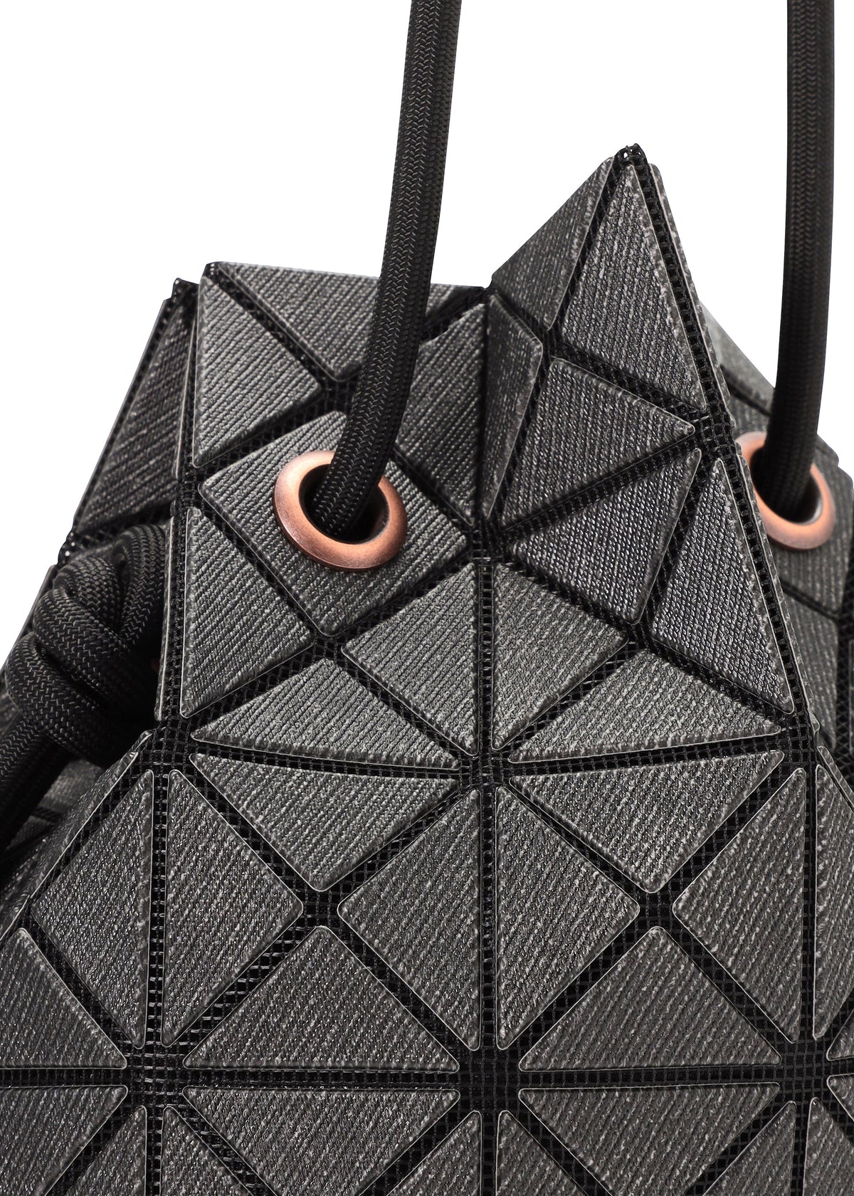 Close-up of the WRING DENIM bag by BAO BAO ISSEY MIYAKE, a black geometric drawstring bag with triangle patterns and black cords threaded through copper-toned metal eyelets. view 4 of 7