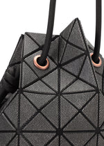 Close-up of the WRING DENIM bag by BAO BAO ISSEY MIYAKE, a black geometric drawstring bag with triangle patterns and black cords threaded through copper-toned metal eyelets.